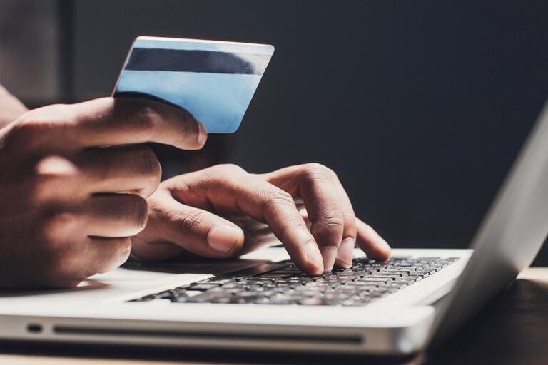 Person holding a credit card and typing on a laptop